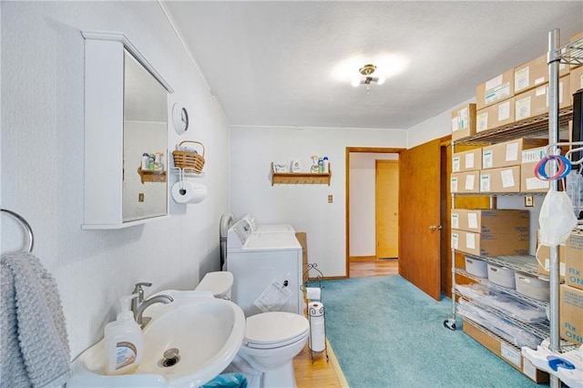 bathroom featuring independent washer and dryer, toilet, and a sink