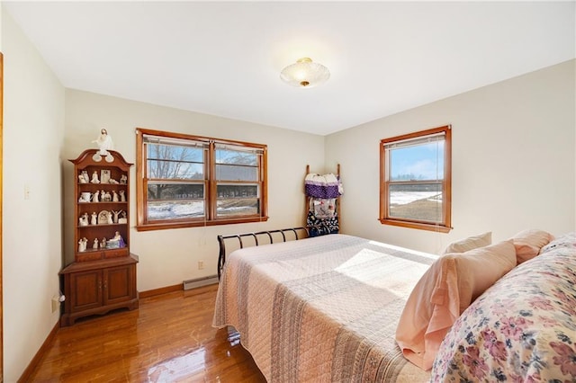 bedroom with a baseboard radiator, baseboards, and wood finished floors