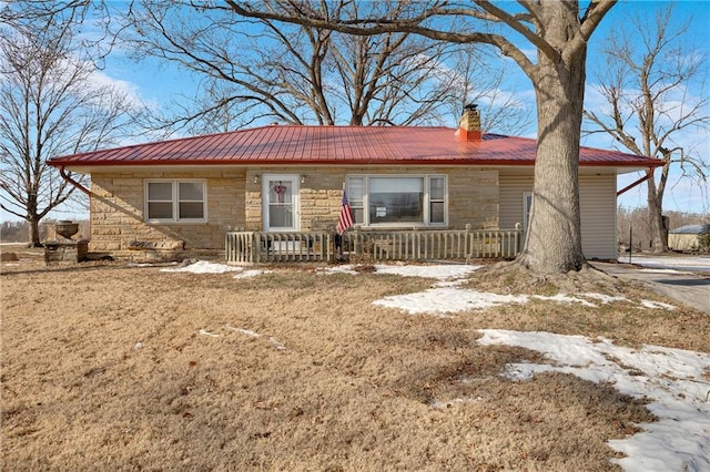 single story home featuring a chimney, stone siding, and metal roof