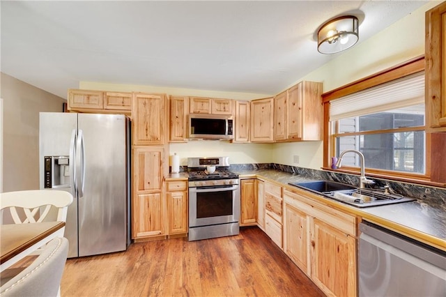 kitchen with dark countertops, a sink, light brown cabinetry, stainless steel appliances, and dark wood-style flooring