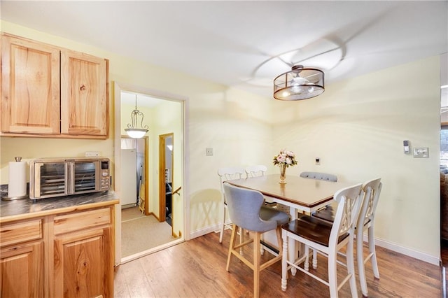 dining space featuring baseboards, light wood-style floors, and a toaster