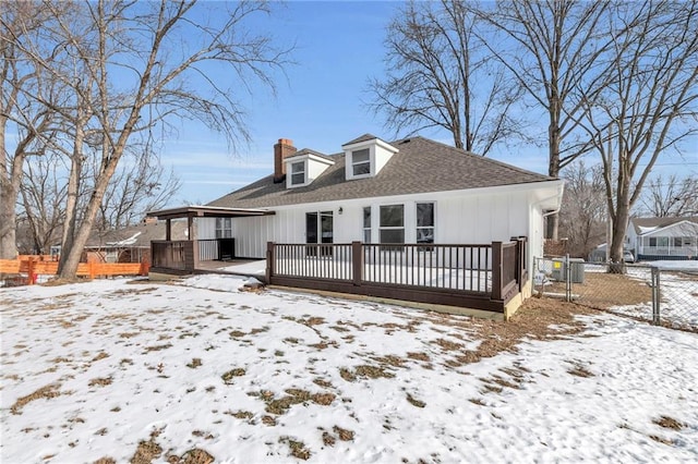 snow covered back of property featuring a deck