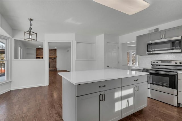 kitchen featuring appliances with stainless steel finishes, gray cabinetry, a center island, a healthy amount of sunlight, and decorative light fixtures