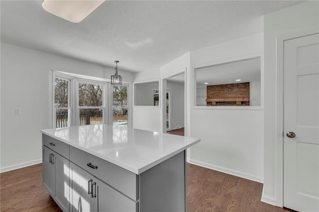 kitchen featuring a center island, a textured ceiling, dark hardwood / wood-style floors, gray cabinets, and pendant lighting