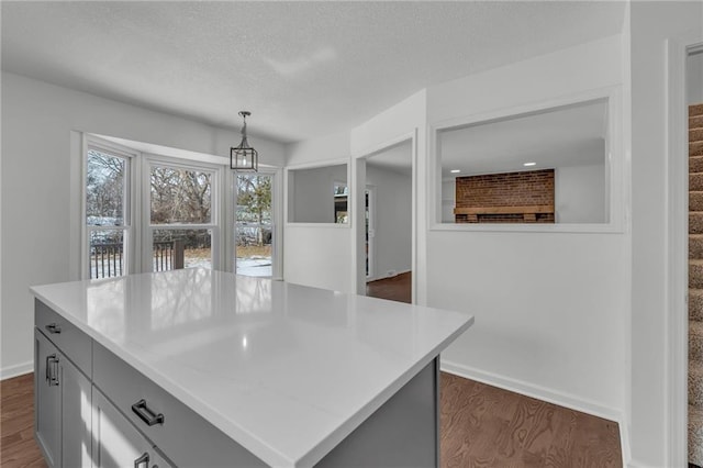 kitchen with gray cabinets, dark hardwood / wood-style floors, pendant lighting, a center island, and a textured ceiling