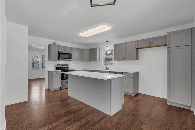 kitchen with sink, gray cabinetry, a center island, stainless steel appliances, and dark wood-type flooring