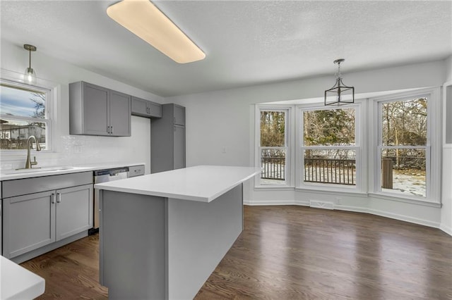 kitchen featuring decorative light fixtures, gray cabinets, sink, and a kitchen island