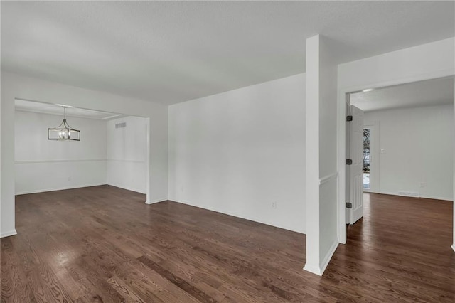 unfurnished room featuring dark hardwood / wood-style floors and a chandelier