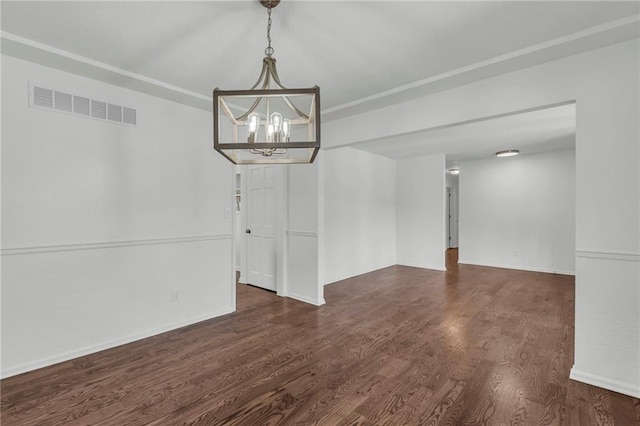 spare room featuring dark wood-type flooring and a chandelier