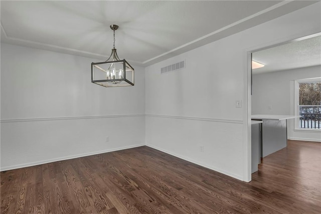 unfurnished dining area with dark hardwood / wood-style flooring and a chandelier