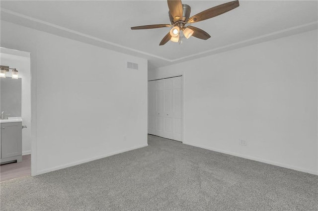 carpeted spare room featuring ceiling fan and sink