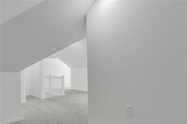 additional living space featuring vaulted ceiling and light colored carpet