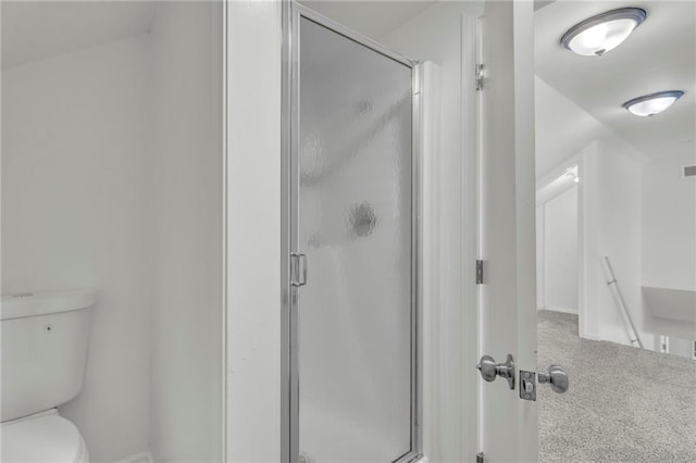 bathroom featuring a shower with door and toilet