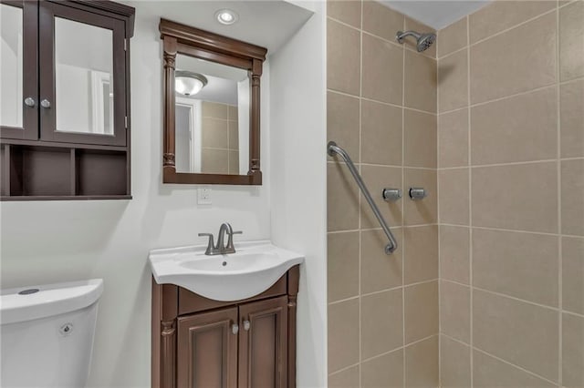 bathroom with tiled shower, vanity, and toilet