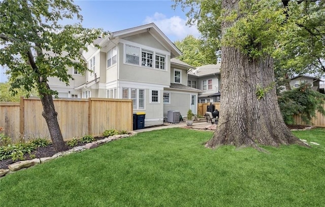 back of house with a yard, fence, and central AC unit