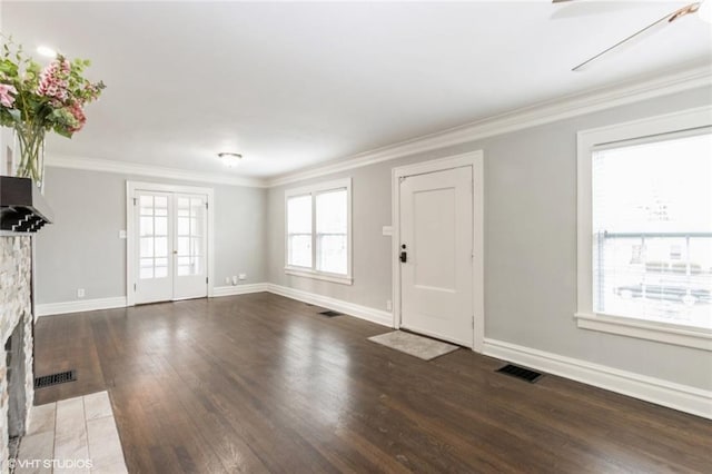 entrance foyer featuring ornamental molding, visible vents, a fireplace, and dark wood-type flooring