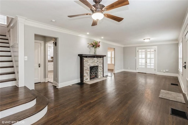 unfurnished living room featuring a fireplace, visible vents, dark wood-type flooring, ornamental molding, and stairs