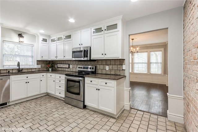 kitchen featuring stainless steel appliances, white cabinets, a sink, and glass insert cabinets