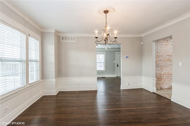 spare room with an inviting chandelier, dark wood-style floors, visible vents, and crown molding