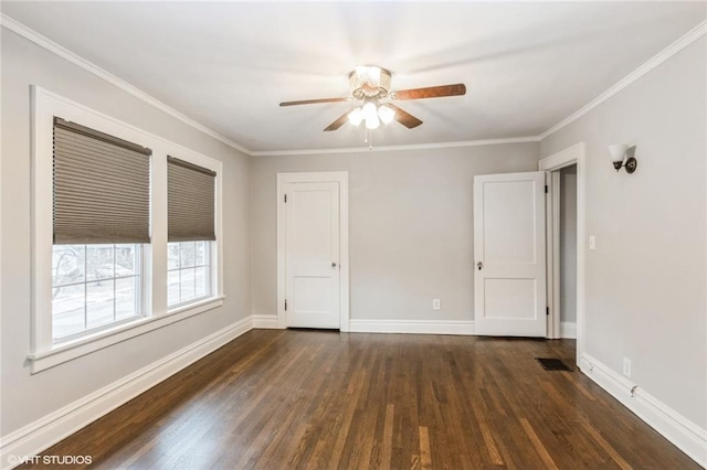 spare room featuring visible vents, dark wood-type flooring, ornamental molding, ceiling fan, and baseboards