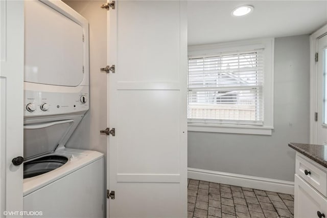 washroom with stacked washer and clothes dryer and baseboards