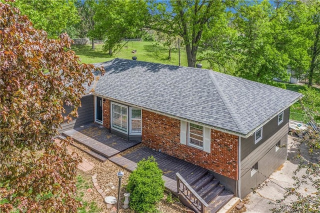 10609 NW Meadow Lane Dr, Parkville, MO 64152 - exterior space with brick siding, a shingled roof, a wooden deck, and a yard