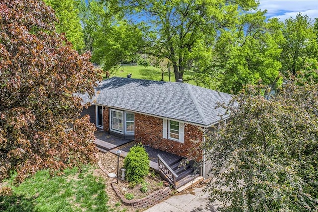 10609 NW Meadow Lane Dr, Parkville, MO 64152 - view of property exterior featuring a lawn, brick siding, a wooden deck, and roof with shingles