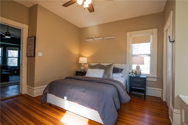 bedroom with dark wood-style floors, lofted ceiling, ceiling fan, and baseboards