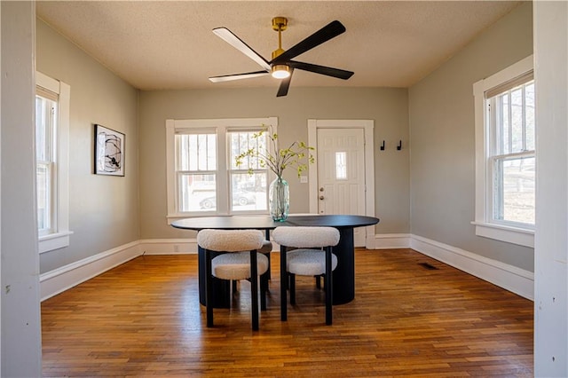 dining space with a textured ceiling, dark wood-style flooring, visible vents, and baseboards