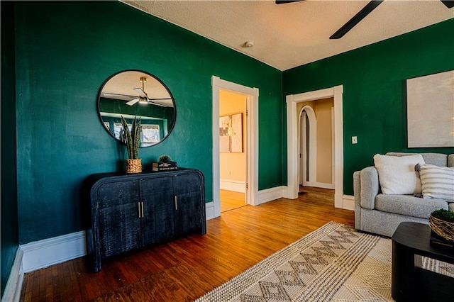 living area featuring baseboards, a ceiling fan, and wood finished floors