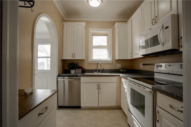 kitchen featuring white appliances, dark countertops, a sink, and white cabinets