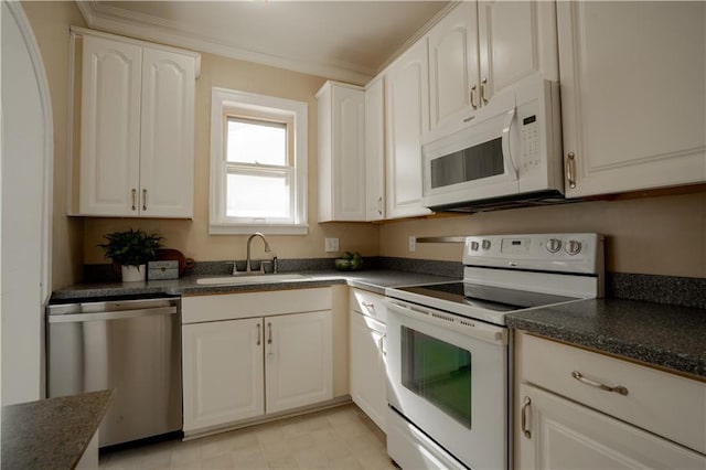 kitchen with white appliances, a sink, white cabinetry, ornamental molding, and dark countertops