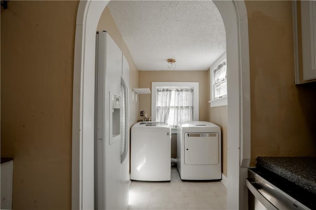 washroom with arched walkways, laundry area, washer and clothes dryer, and a textured ceiling