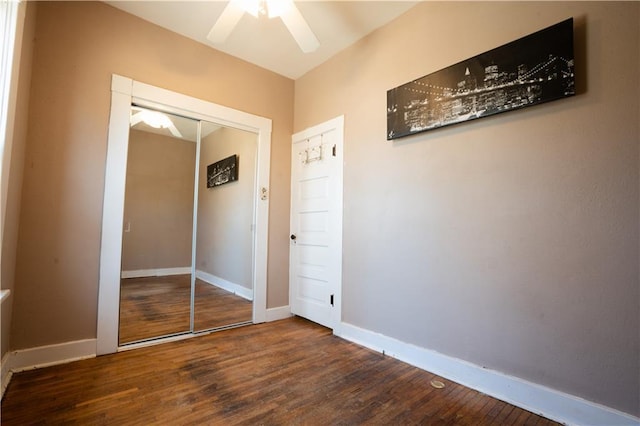 unfurnished bedroom featuring ceiling fan, a closet, baseboards, and wood finished floors