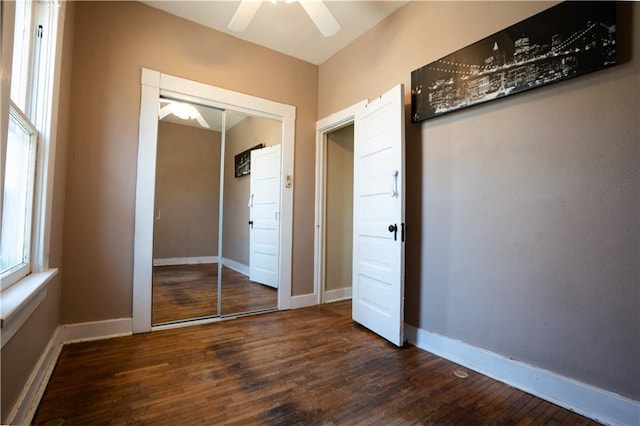 unfurnished bedroom featuring dark wood-style floors, a ceiling fan, baseboards, and a closet