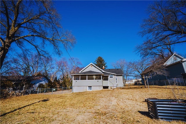 rear view of property with a yard, fence, and a sunroom