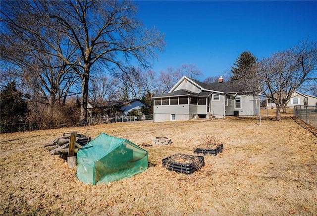 view of front of property with a fire pit, fence, and a sunroom