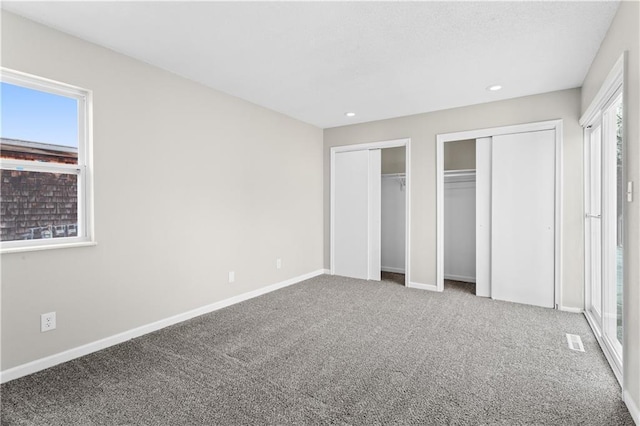 unfurnished bedroom featuring multiple windows, multiple closets, and carpet