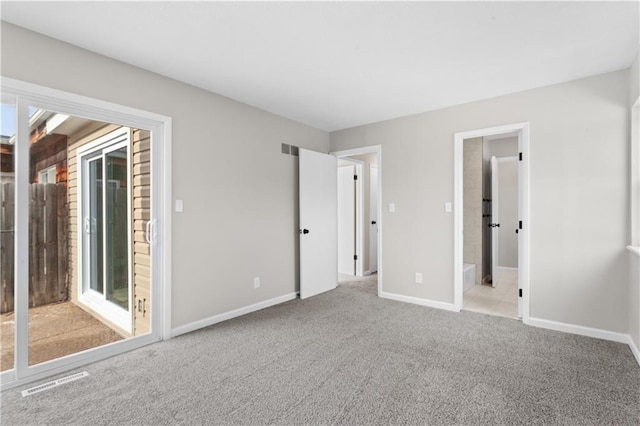 unfurnished bedroom featuring light carpet and ensuite bath