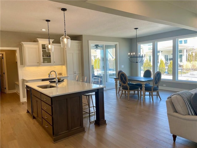 kitchen with tasteful backsplash, sink, white cabinets, and decorative light fixtures