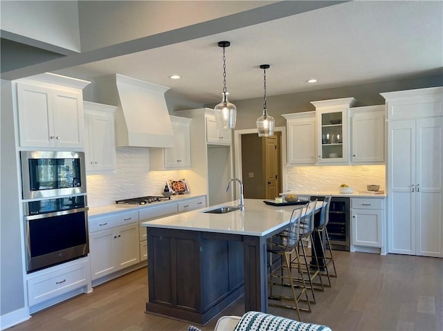 kitchen with sink, white cabinets, stainless steel appliances, a center island with sink, and light hardwood / wood-style flooring