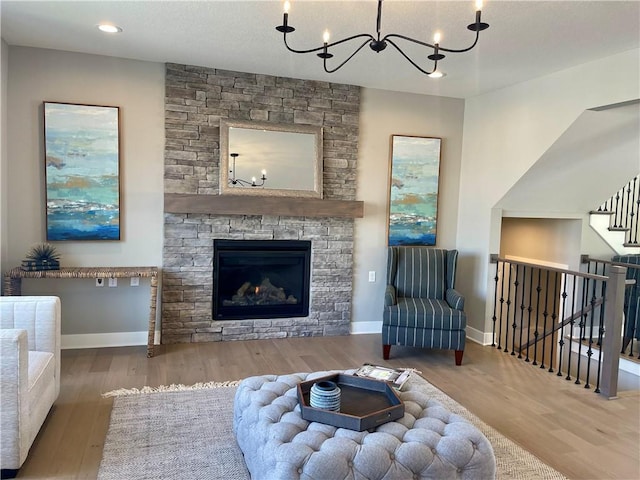 sitting room featuring an inviting chandelier, hardwood / wood-style floors, and a stone fireplace