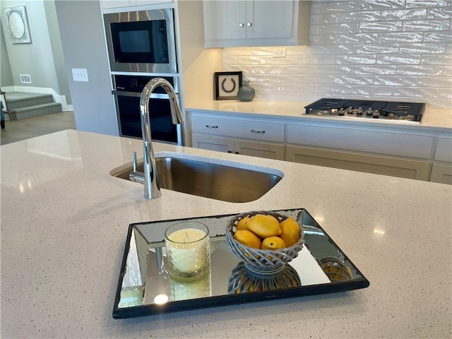 kitchen featuring white cabinetry, stainless steel appliances, sink, and backsplash