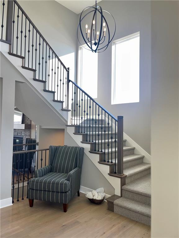 stairs featuring wood-type flooring, a fireplace, a chandelier, and a high ceiling