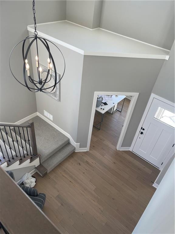 stairs with high vaulted ceiling, a chandelier, and hardwood / wood-style floors