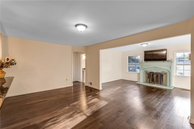 unfurnished living room featuring dark wood-type flooring and plenty of natural light