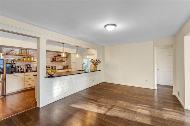 interior space featuring dark wood-type flooring, decorative light fixtures, stainless steel refrigerator, and sink