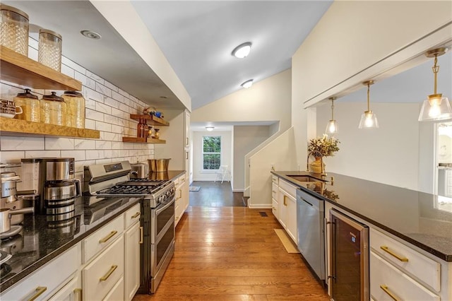 kitchen with tasteful backsplash, appliances with stainless steel finishes, white cabinetry, and pendant lighting