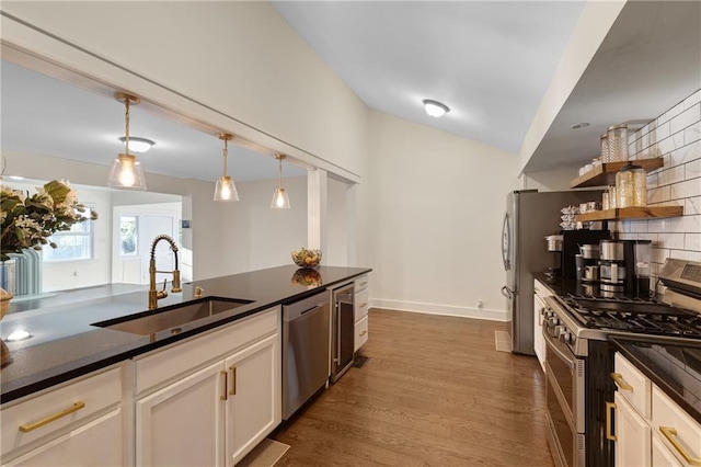 kitchen with appliances with stainless steel finishes, white cabinets, decorative light fixtures, decorative backsplash, and sink