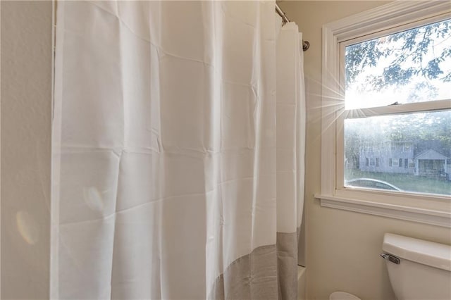 bathroom featuring toilet and shower / bathtub combination with curtain